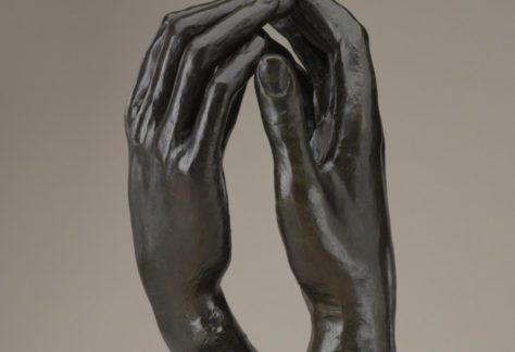 A sculpture of two right hands facing each other with fingertips touching.