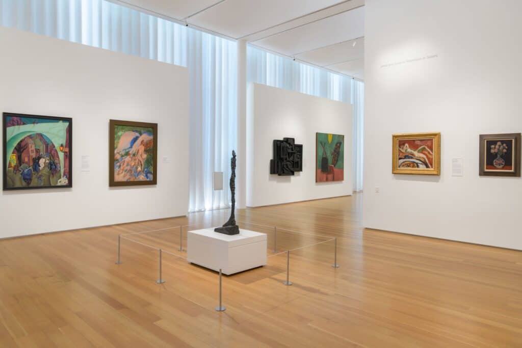 Twenty-first-century paintings and sculptures displayed in a white cube art gallery with hardwood floors.