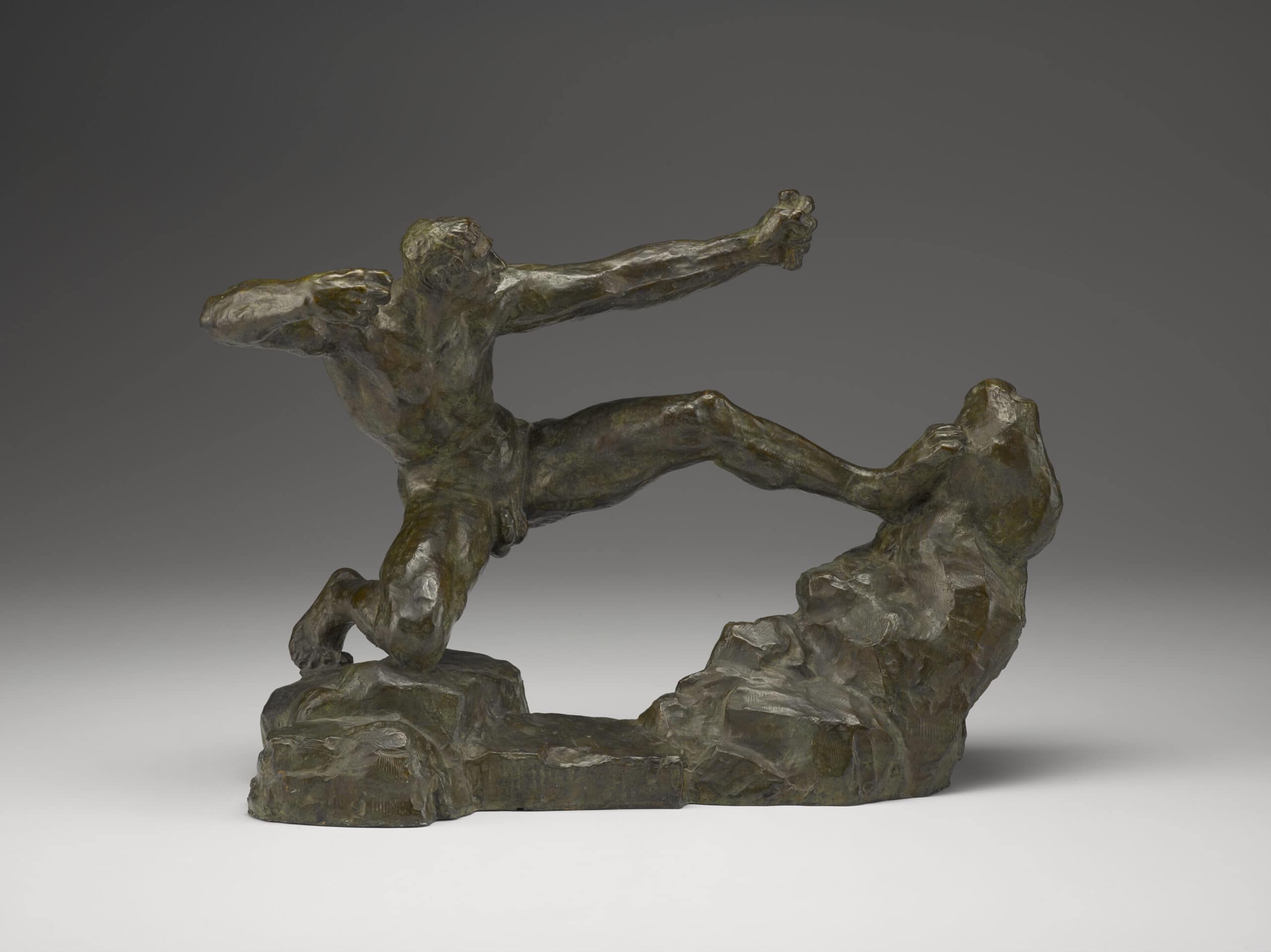 A bronze sculpture of a man kneeling on a rock formation and drawing an nonexistent bow and arrow. 