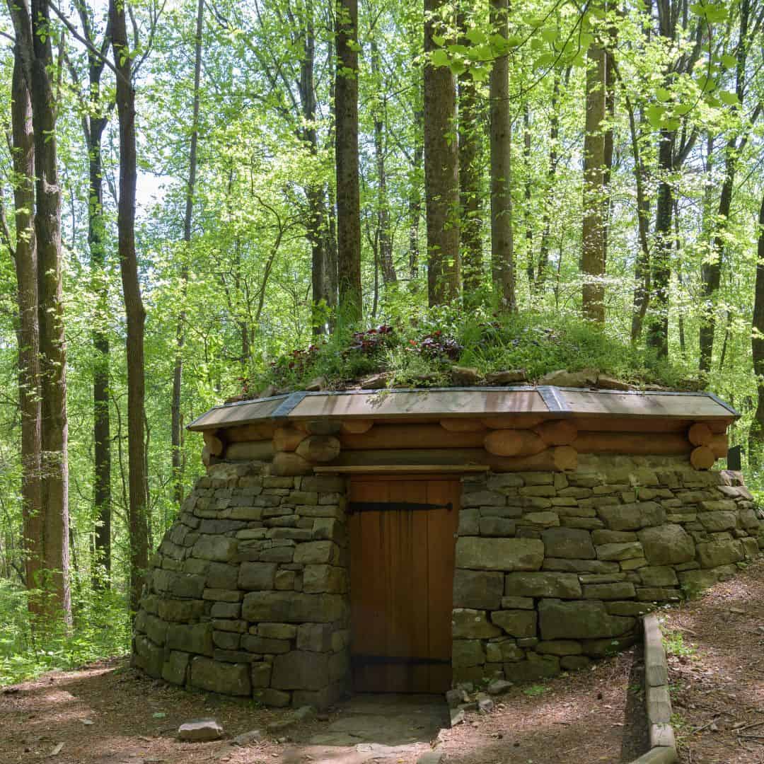 A stone and wood hut nestled in a wooded area.