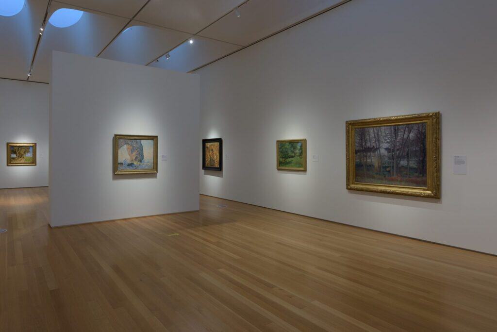 A white-cube art gallery with early modernist landscapes hung on the walls.