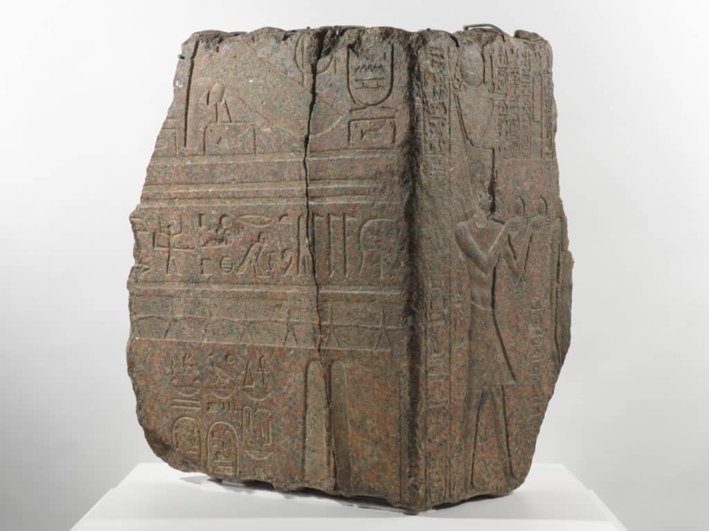 A piece of granite with a human figure and hieroglyphic symbols carved into its surface.