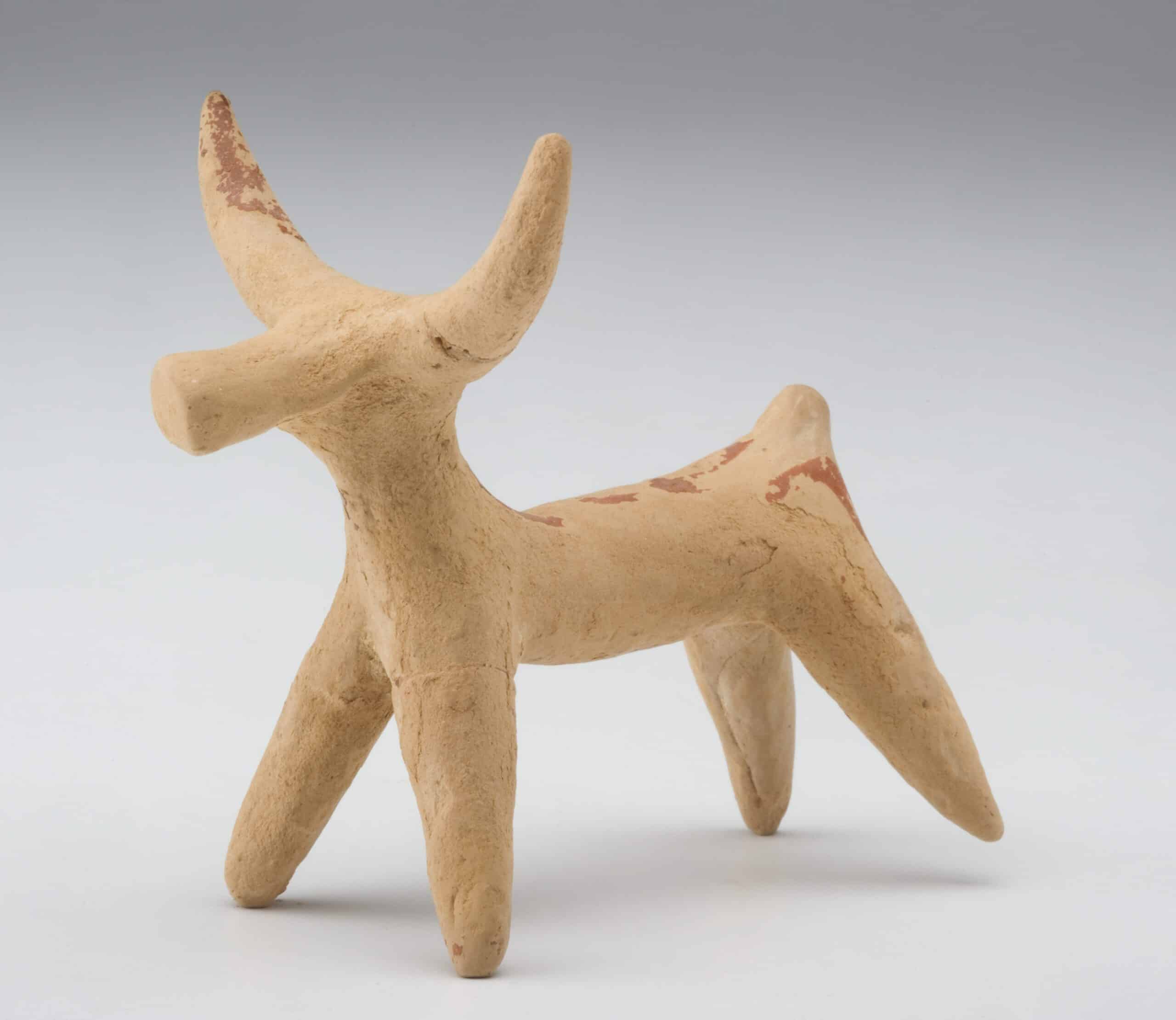A beige terracotta figurine of a bull. 