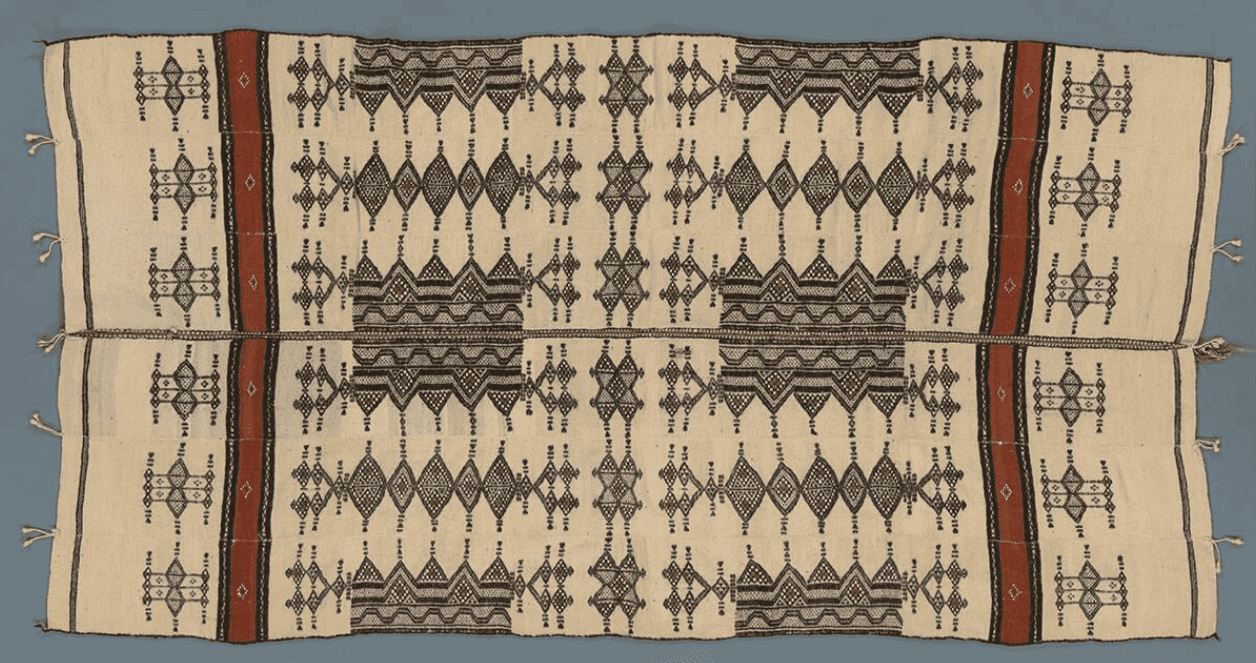 A handspun wool blanket with symmetrical, decorative black and red designs. 