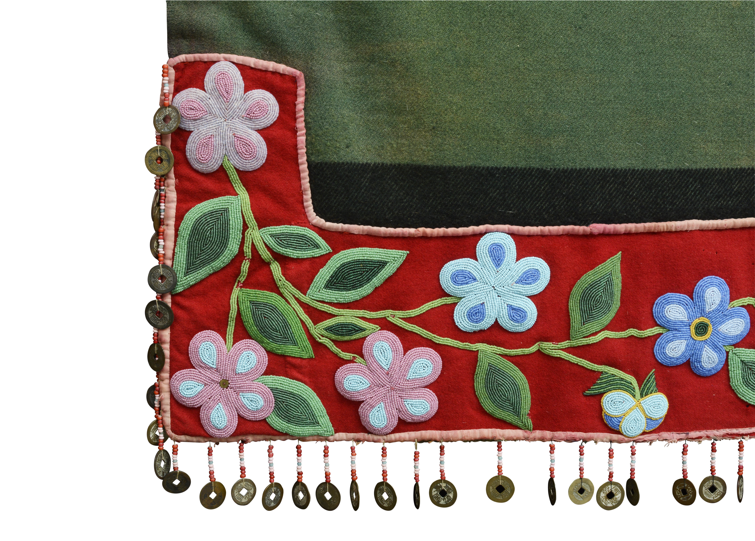 The corner of a green blanket with red trim embroidered with beads and a fringe edge with coins.
