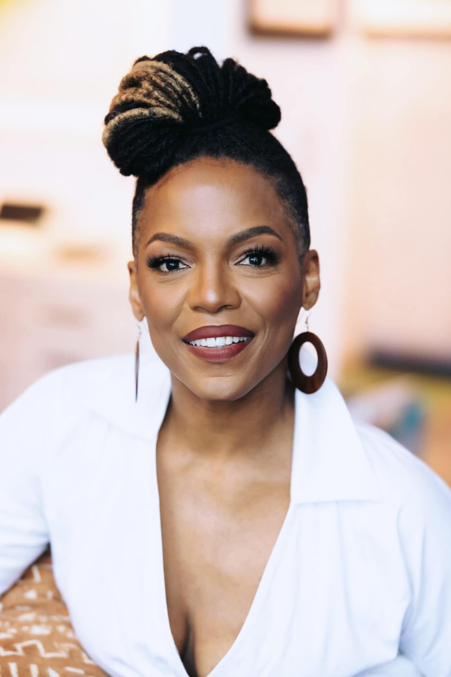 Headshot of a woman with her hair up, wearing a white blouse and black, circular earrings.