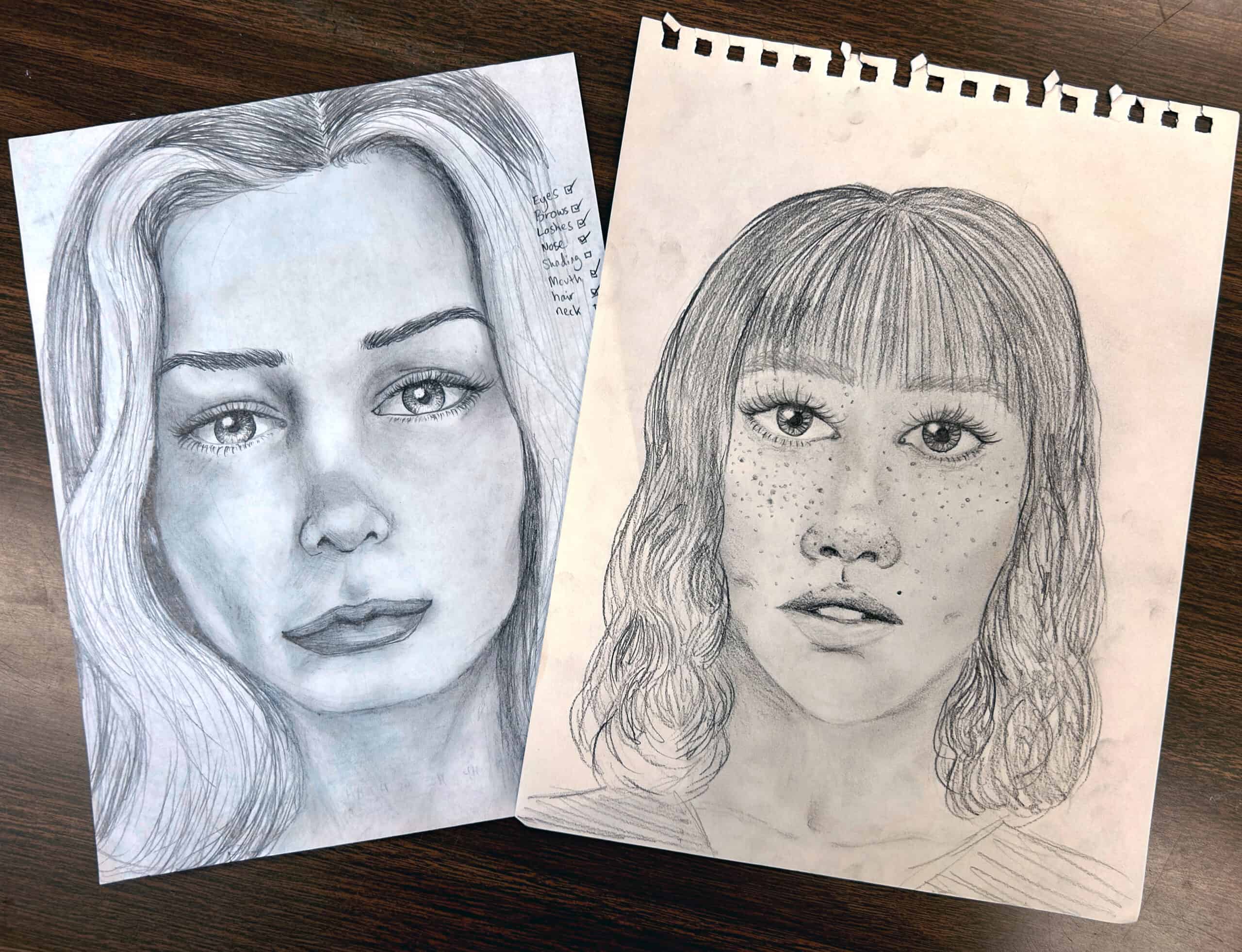 Two pencil-drawn portraits of teenage girls placed on a desk.