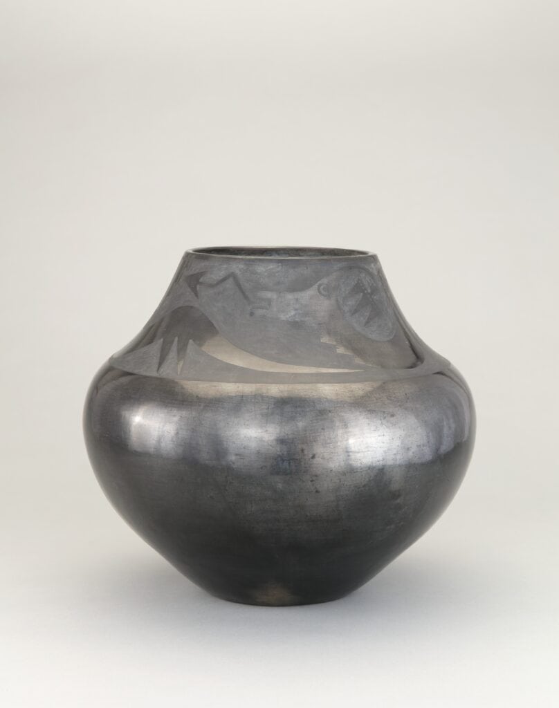 A black jar with black decorative designs surrounding the opening.