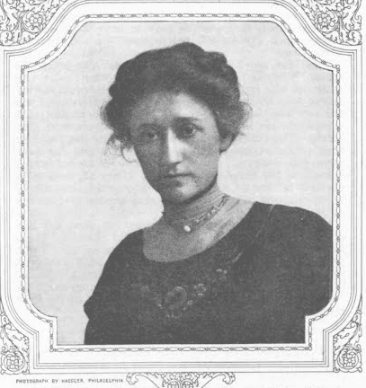 A black and white portrait of a woman with her hair up wearing a high-collared dress with a floral design. 