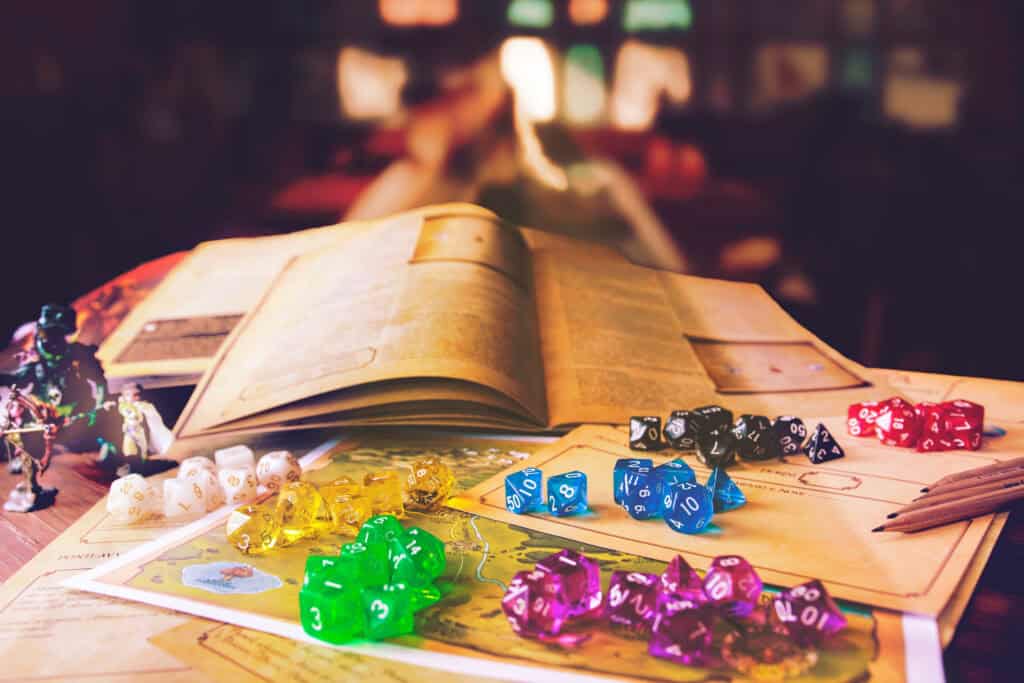Various multicolored dice sit atop Dungeons & Dragons character sheets surrounded by maps, pencils, and figurines.