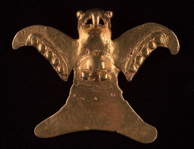 Small gold sculpture of an eagle with outstretched wings and a large beak.