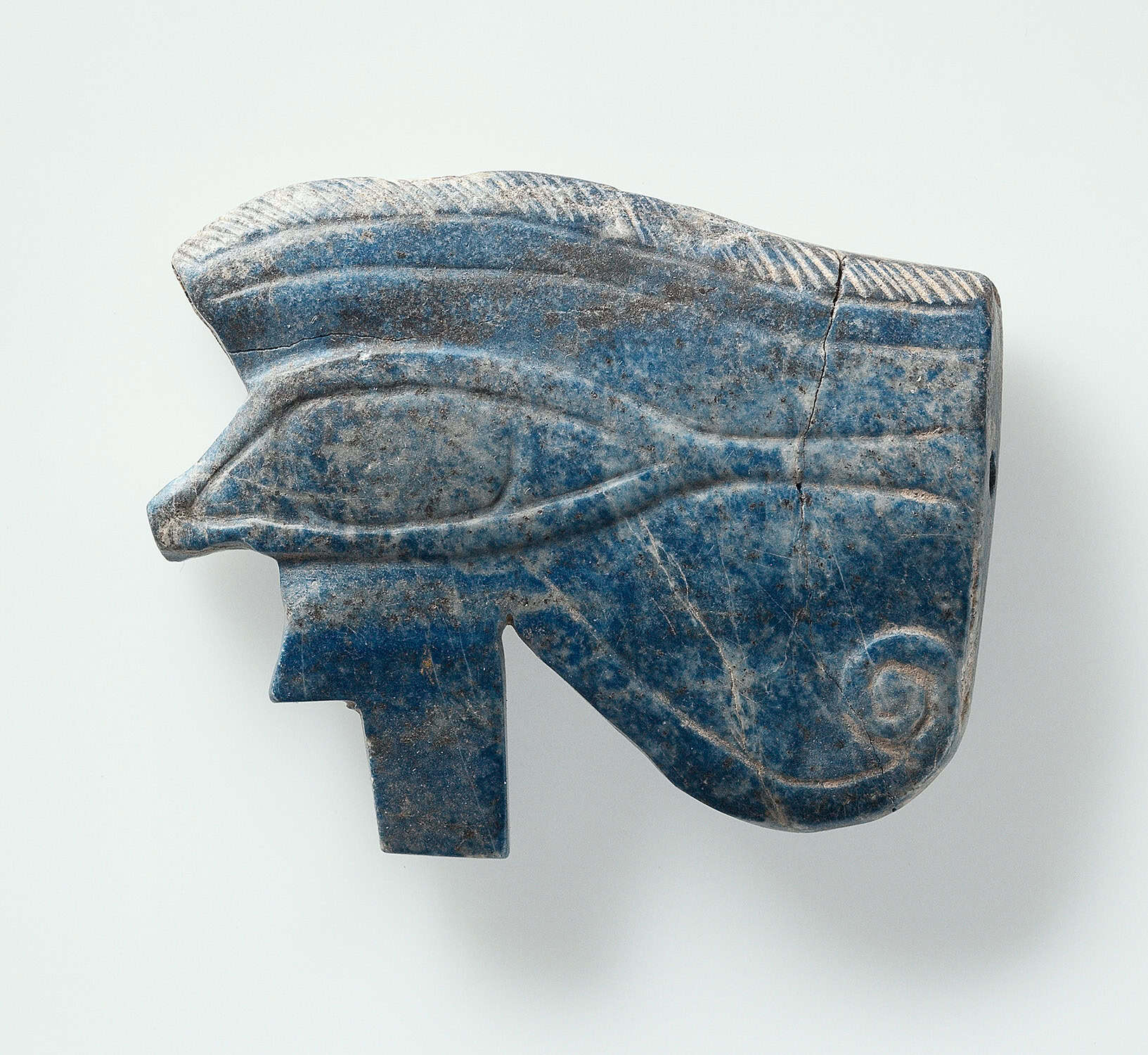 Stone amulet featuring a left eye with straight and curling lines radiating from the outer corner.