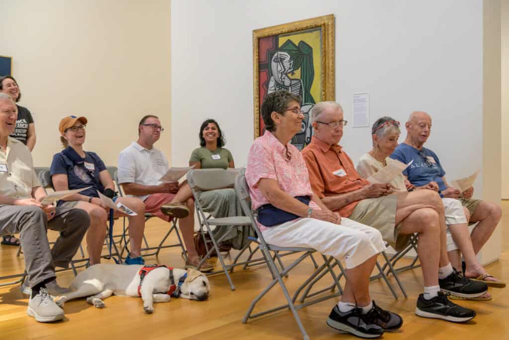 People sit in a gallery space engaging with the art in front of them. This image was taken by Rachel.